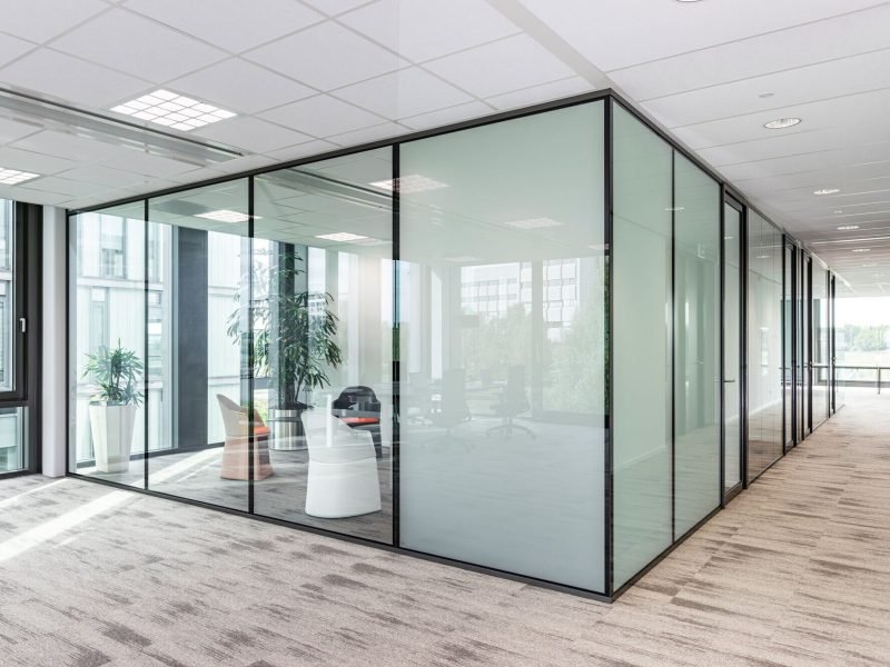 Corner glass cabin with full-height framed partitions in an open-plan office